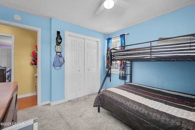 carpeted bedroom with ceiling fan, a closet, and a textured ceiling