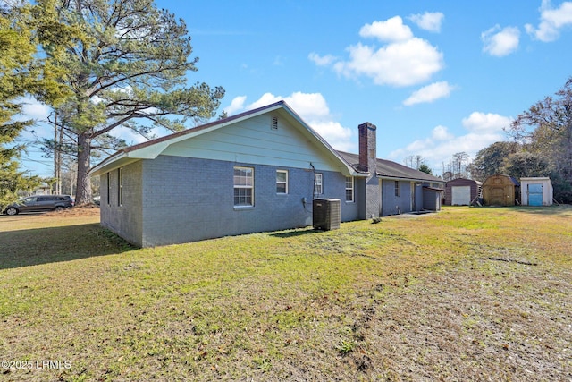 back of property with a lawn, cooling unit, and a storage shed