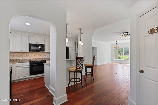 kitchen with black appliances, a ceiling fan, arched walkways, tasteful backsplash, and white cabinetry