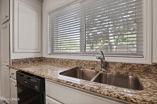 kitchen with dishwasher, a sink, light stone counters, and white cabinetry