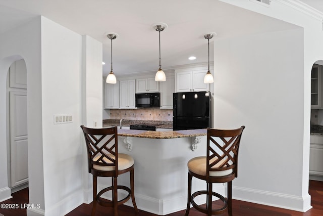 kitchen with black appliances, baseboards, a breakfast bar, arched walkways, and recessed lighting