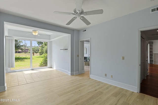 empty room with light wood-type flooring, a ceiling fan, and baseboards