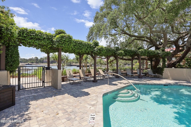 community pool featuring fence, a patio, and a water view