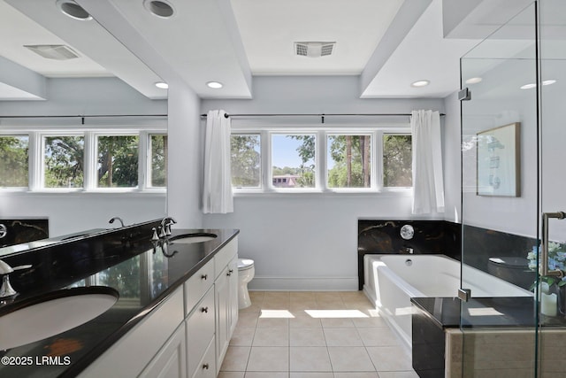 full bath with toilet, baseboards, tile patterned flooring, double vanity, and a garden tub