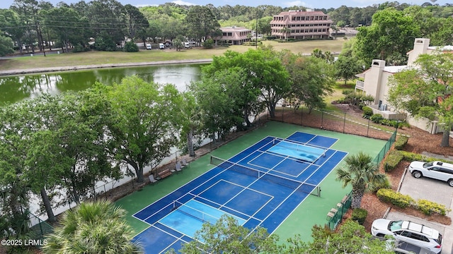 view of tennis court featuring fence and a water view