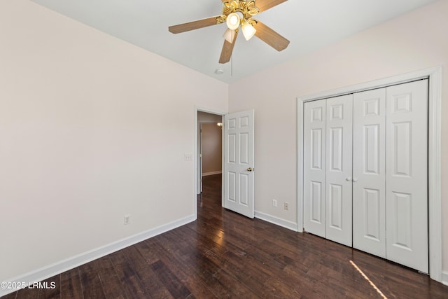 unfurnished bedroom featuring dark wood-style floors, a closet, baseboards, and a ceiling fan