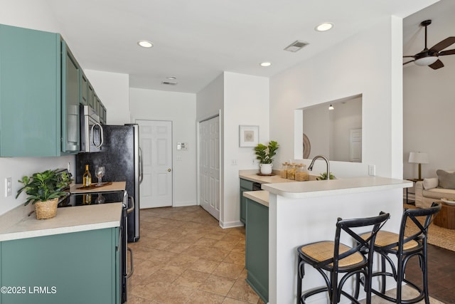 kitchen with visible vents, stainless steel microwave, a breakfast bar, light countertops, and green cabinetry