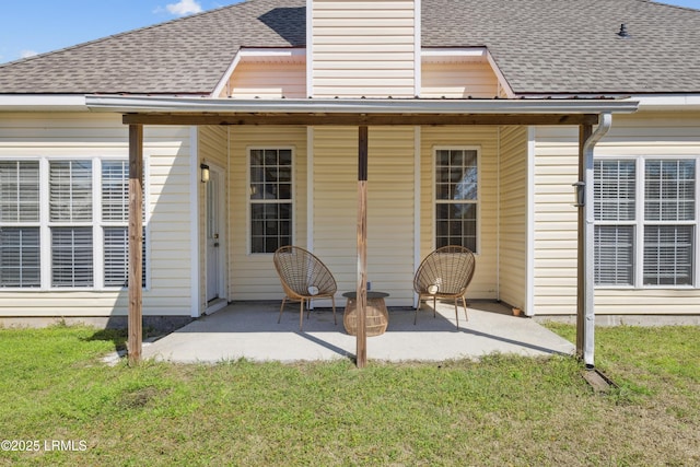 rear view of house with a yard, a patio, a chimney, and a shingled roof