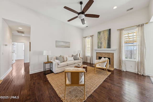 living room featuring visible vents, a tiled fireplace, a ceiling fan, hardwood / wood-style flooring, and baseboards