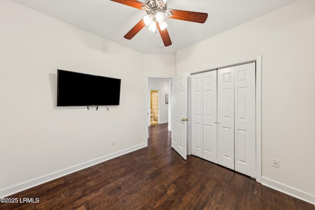 unfurnished bedroom with a closet, baseboards, dark wood-type flooring, and a ceiling fan