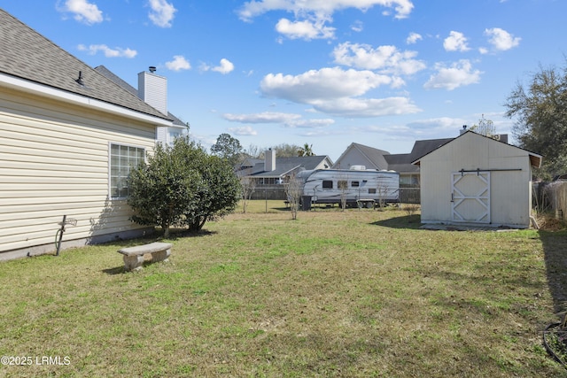 view of yard featuring a storage unit, an outbuilding, and fence