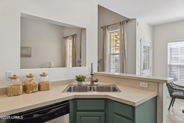 kitchen with green cabinets, dishwasher, light countertops, light tile patterned floors, and a sink