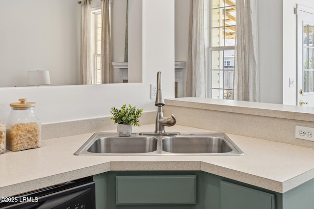 interior details featuring green cabinetry, dishwasher, light countertops, and a sink