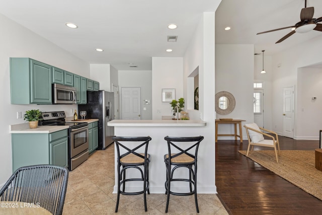 kitchen featuring visible vents, light countertops, a kitchen bar, appliances with stainless steel finishes, and a ceiling fan