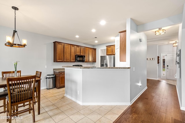 109 Patriot Ct, Beaufort, SC 29906 - kitchen with stainless steel refrigerator with ice dispenser, black microwave, a chandelier, brown cabinets, and light stone counters