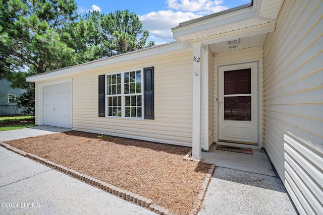 view of exterior entry featuring concrete driveway and an attached garage