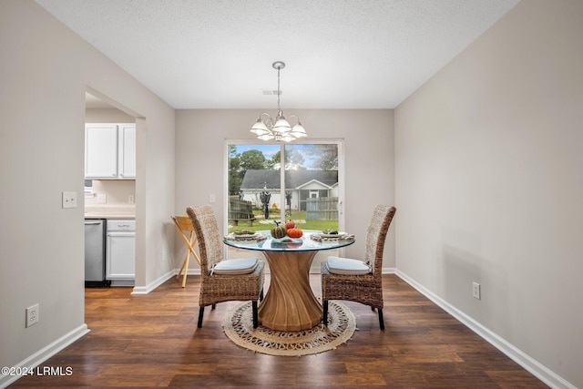 dining area featuring a chandelier, a textured ceiling, dark wood-type flooring, and baseboards