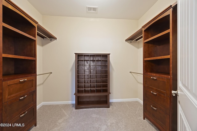 walk in closet featuring light colored carpet