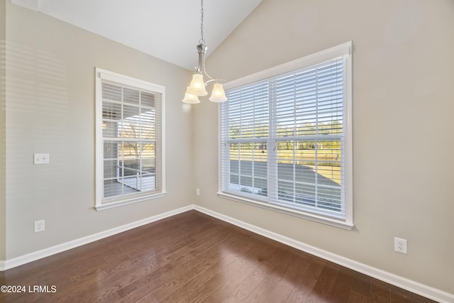 unfurnished dining area with dark hardwood / wood-style flooring, a chandelier, and vaulted ceiling