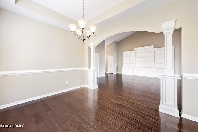 empty room featuring a notable chandelier, dark hardwood / wood-style floors, and ornate columns