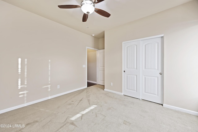 unfurnished bedroom featuring light carpet, ceiling fan, and a closet