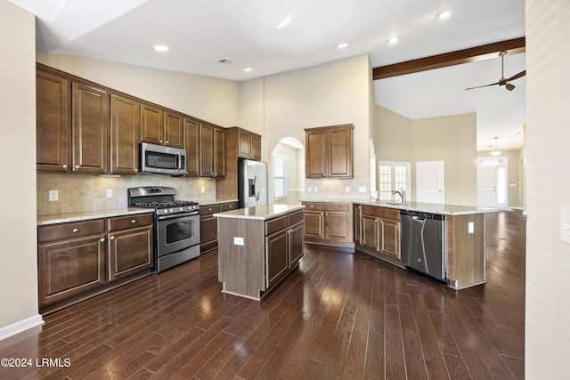 kitchen with a kitchen island, high vaulted ceiling, tasteful backsplash, sink, and stainless steel appliances