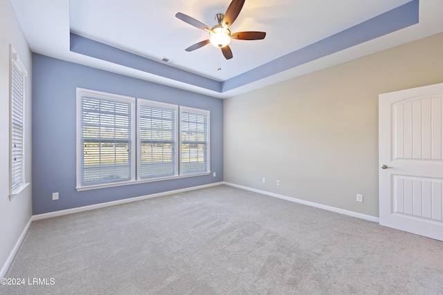 carpeted spare room featuring a raised ceiling and ceiling fan