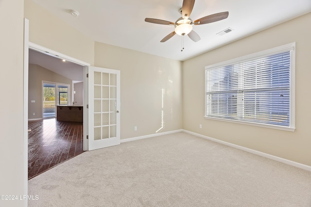 empty room with french doors, ceiling fan, lofted ceiling, and carpet flooring