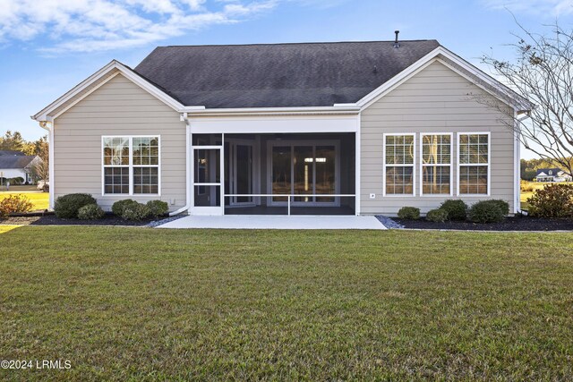 back of property with a lawn, a sunroom, and a patio area