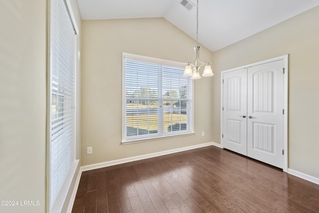 unfurnished dining area with dark wood-type flooring, a chandelier, and vaulted ceiling