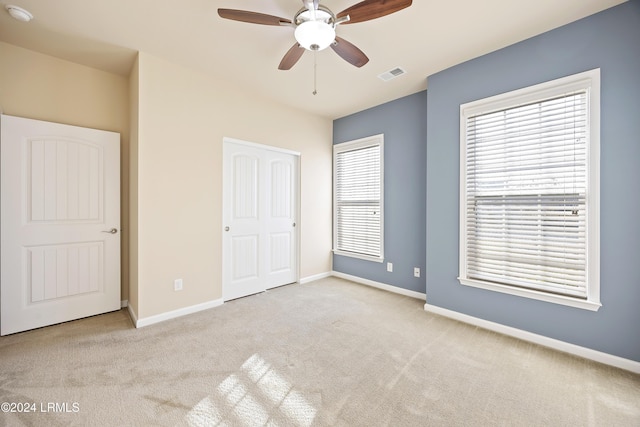 unfurnished bedroom with multiple windows, light carpet, a closet, and ceiling fan