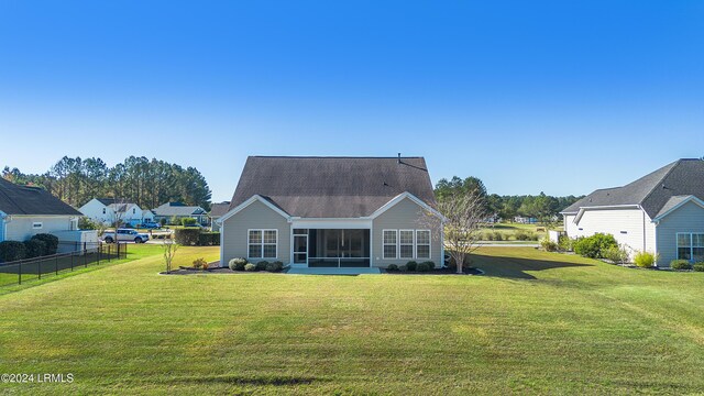 rear view of property featuring a sunroom and a lawn