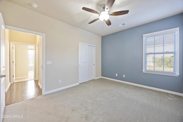 unfurnished bedroom with light colored carpet, a closet, and ceiling fan