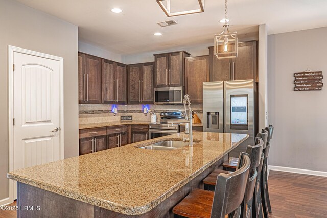 kitchen with dark wood-style flooring, dark brown cabinetry, baseboards, a sink, and stainless steel appliances