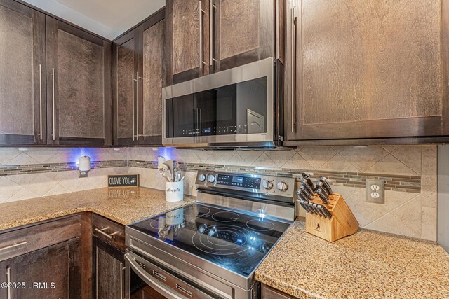 kitchen with appliances with stainless steel finishes, dark brown cabinetry, backsplash, and light stone counters