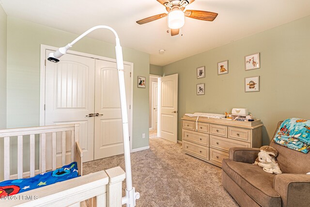 bedroom with ceiling fan, light colored carpet, baseboards, and a closet