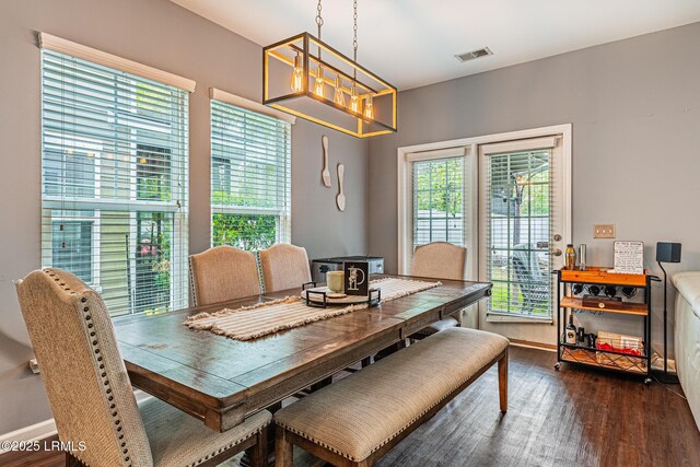 dining room with visible vents, baseboards, wood finished floors, and a notable chandelier