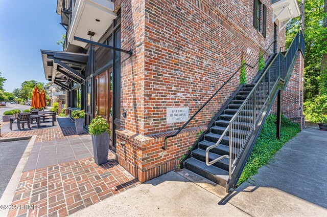 view of home's exterior featuring stairs, a patio area, and brick siding