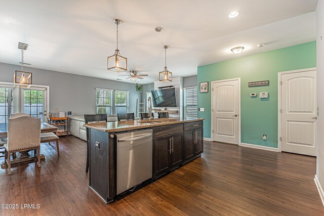 kitchen with stainless steel dishwasher, baseboards, a center island with sink, and dark wood-type flooring