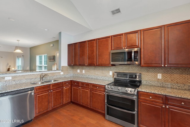 kitchen with stainless steel appliances, sink, and light stone counters