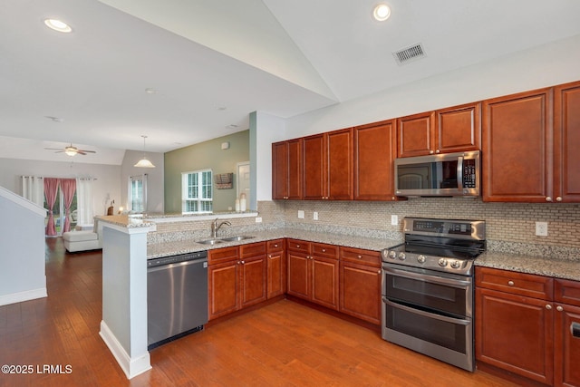 kitchen with vaulted ceiling, appliances with stainless steel finishes, kitchen peninsula, and sink