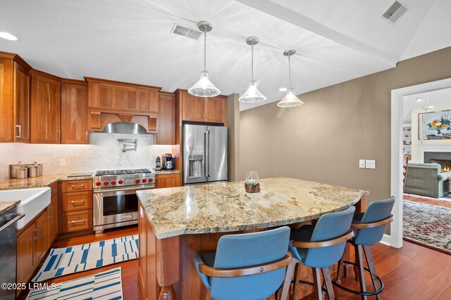 1716 Longfield Dr, Saint Helena Island, SC 29920 - kitchen with high end appliances, dark wood-type flooring, tasteful backsplash, a center island, and brown cabinetry