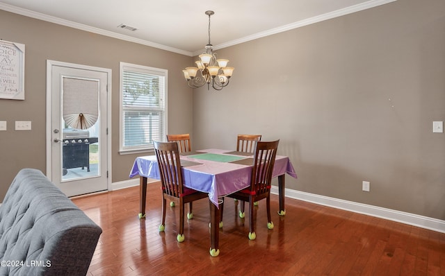 dining space featuring hardwood / wood-style flooring, crown molding, and an inviting chandelier