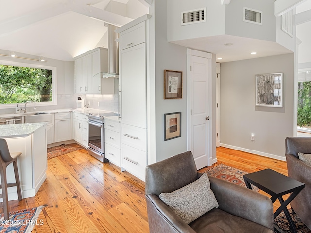 2065 Deer Island Rd, Hilton Head Island, SC 29928 - kitchen with electric range, light wood-type flooring, open floor plan, light countertops, and backsplash
