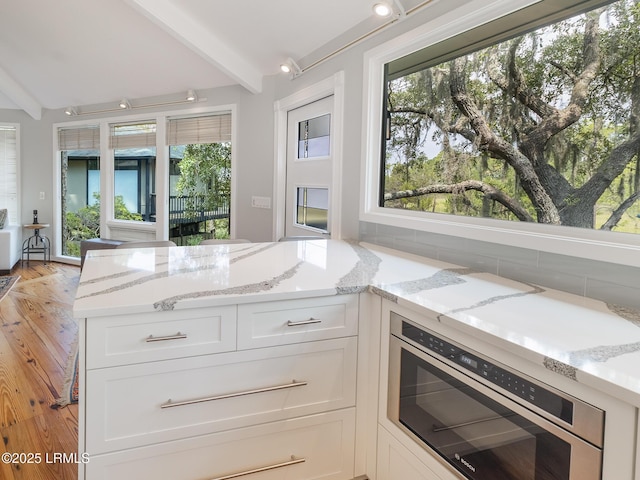 2065 Deer Island Rd, Hilton Head Island, SC 29928 - kitchen with beam ceiling, white cabinets, light stone counters, healthy amount of natural light, and wall oven