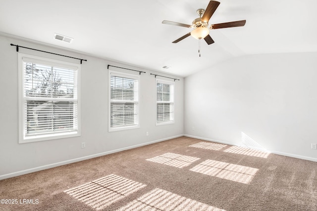 carpeted spare room with baseboards, visible vents, and vaulted ceiling