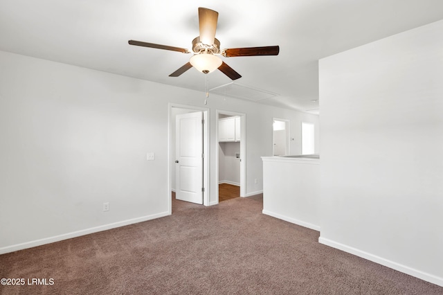 unfurnished room with ceiling fan, carpet floors, attic access, and baseboards