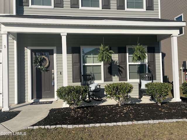 view of exterior entry with board and batten siding and covered porch