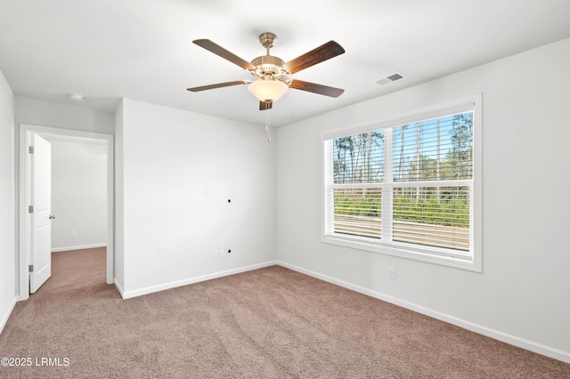 spare room with carpet floors, visible vents, ceiling fan, and baseboards