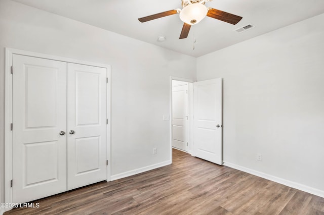 unfurnished bedroom with a closet, visible vents, baseboards, and wood finished floors